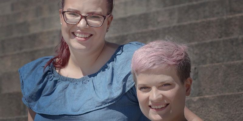 Kaksi naista katsoo kameraan ja hymyilee.