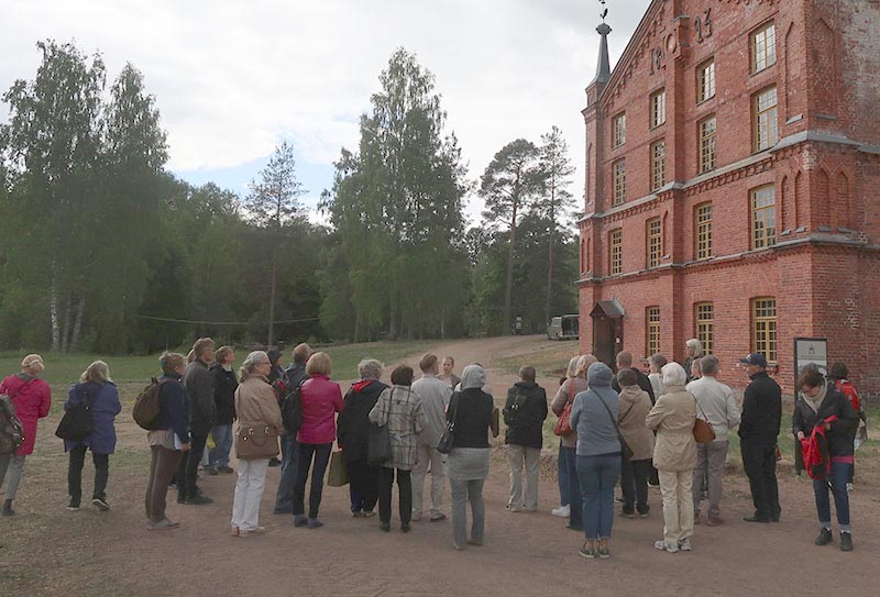 Ihmiset seisovat ulkona vanhan tiilirakennuksen edessä.