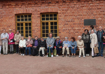 Ihmisiä istumassa vanhan tiilirakennuksen ulkoseinän edessä.