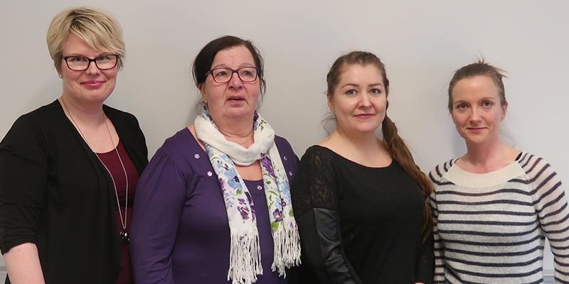 Neljä naista seisovat vierekkäin ja hymyilevät.