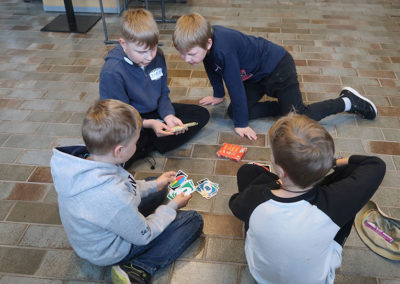 Lapset istuvat maassa ja pelaavat korttipeliä.