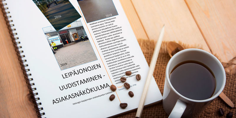 Pöydällä on kynä, muki ja vihko, jossa lukee "leipäjonojen uudistaminen -asiakasnäkökulma"
