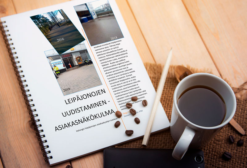Pöydällä on kynä, muki ja vihko, jossa lukee "leipäjonojen uudistaminen -asiakasnäkökulma"