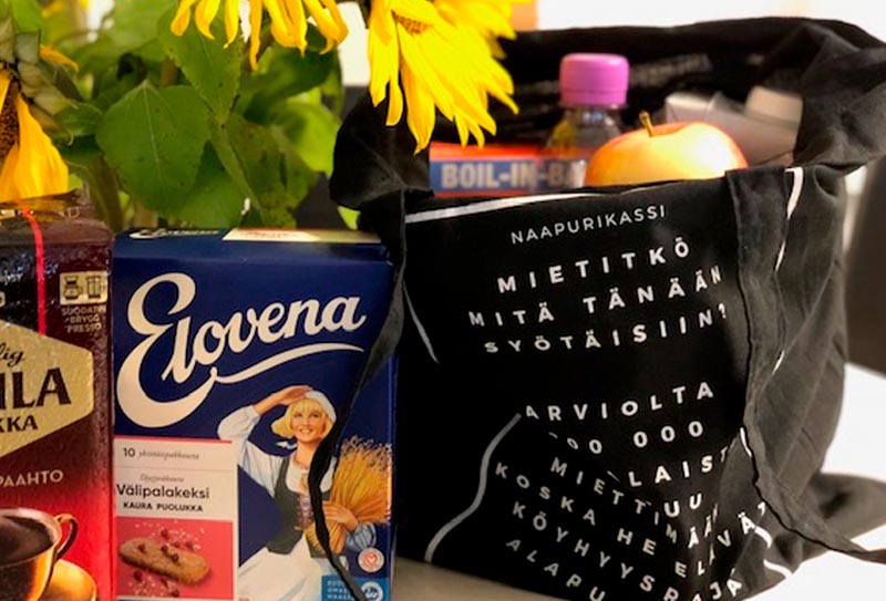 Pöydällä on kahvipaketti, kaurapuuropaketti ja kangaskassi, jossa on ruokatuotteita.