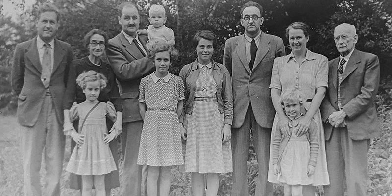 Vanhva mustavalkea valokuva, jossa on yksitoista henkilöä seisomassa ulkona.