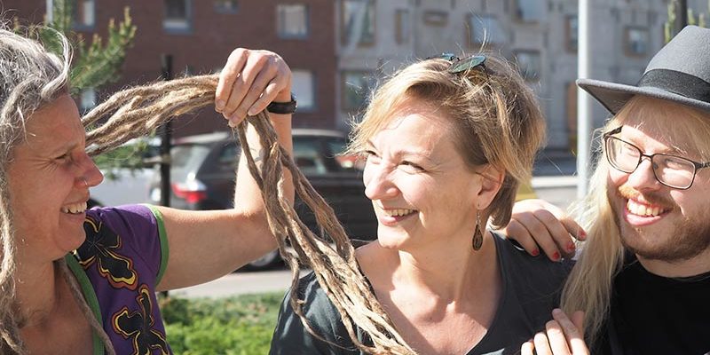 Nainen esittelee rastojaan kahdelle ihmiselle puistonpenkillä.