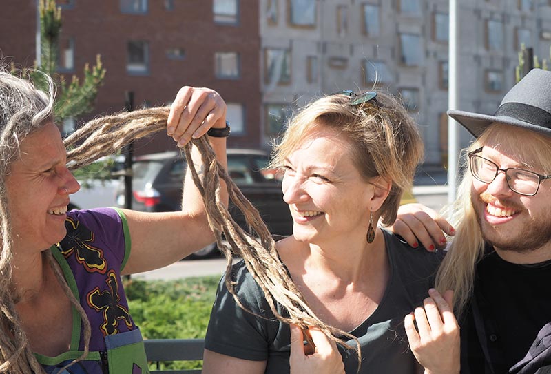 Nainen esittelee rastojaan kahdelle ihmiselle puistonpenkillä.