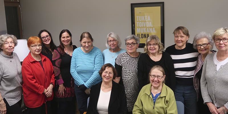 Joukko ihmisiä poseeraa vierekkäin kameralle FinFami Uusimaan kokoushuoneessa.