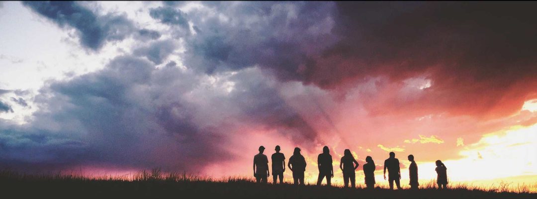 Yhdeksän ihmistä seisoo ulkona vierekkäin.