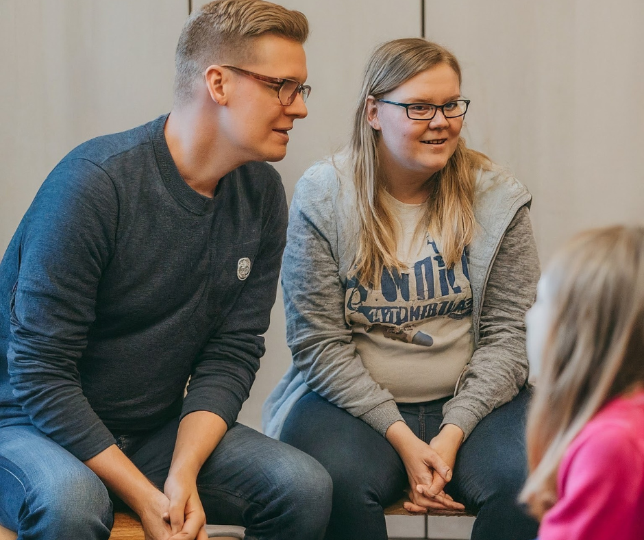 Isä, äiti ja lapsi istuvat tuoleilla vertaistukiryhmässä.