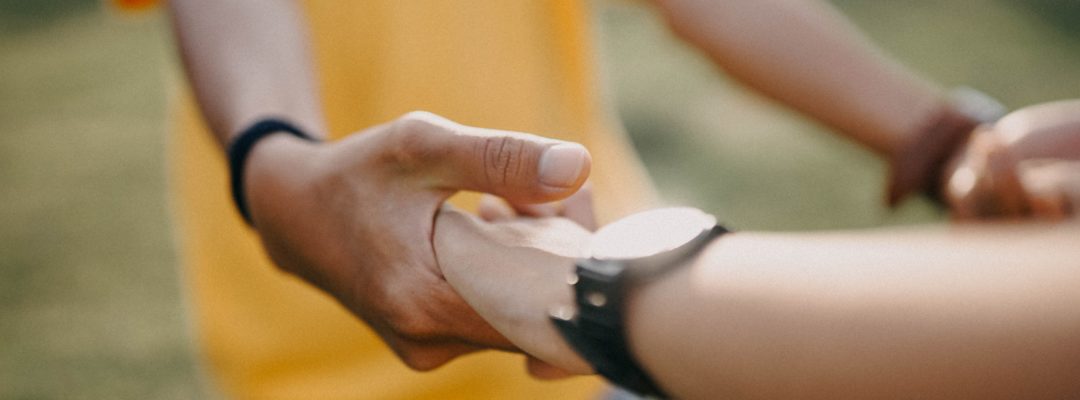 Kaksi ihmistä pitävät toisiaan käsistä kiinni.