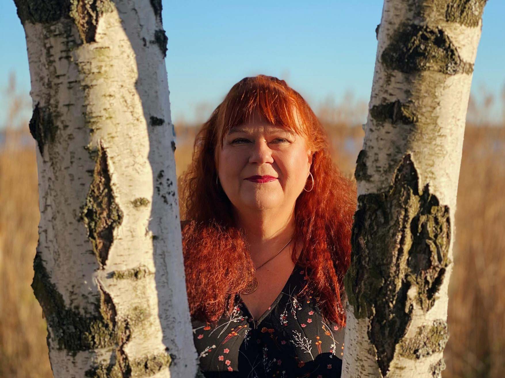 Kokemusasiantuntija Tarja Holmgren katsoo koivinrunkojen välistä