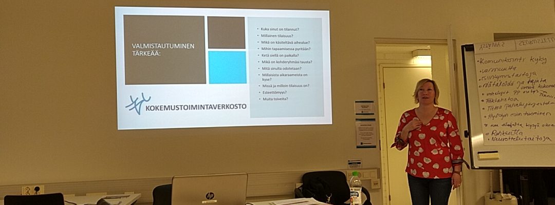 Nainen pitämässä luentoa. Seinälle on heijastettu diaesitys.