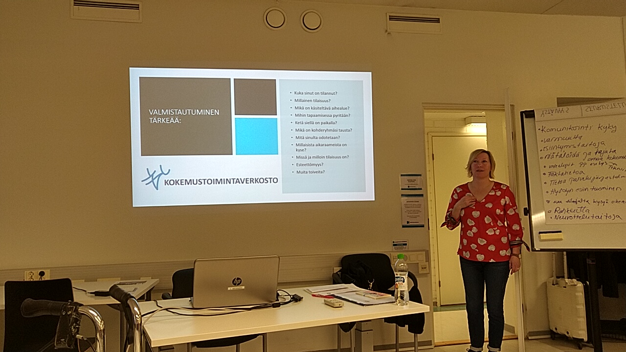 Nainen pitämässä luentoa. Seinälle on heijastettu diaesitys.
