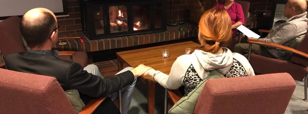 Pariskunta istuu nojatuoleilla ja pitelevät toisiaan kädestä.