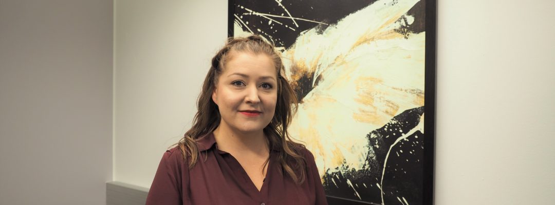 Nainen katsoo kameraan ja hymyilee.