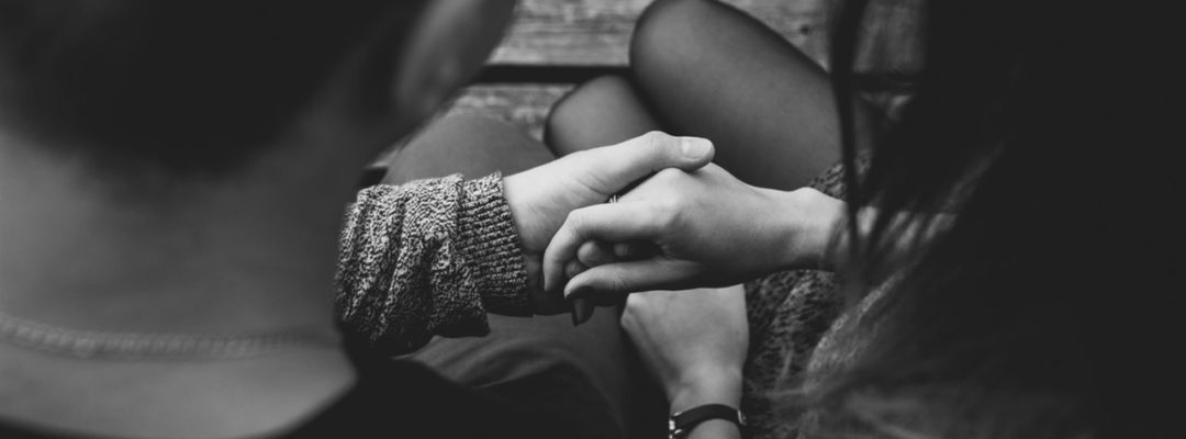 Kaksi henkilöä pitelevät toisiaan kädestä.