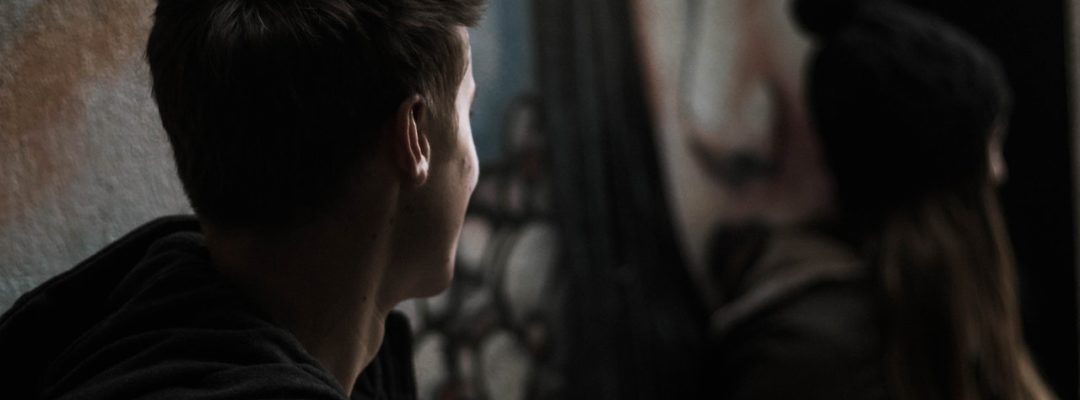 Mies seisoo selin kameraan ja katsoo edessä olevaa naista.