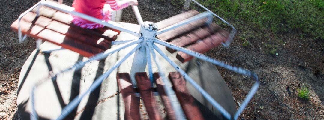 Hellehattuinen lapsi keinuu karusellissa