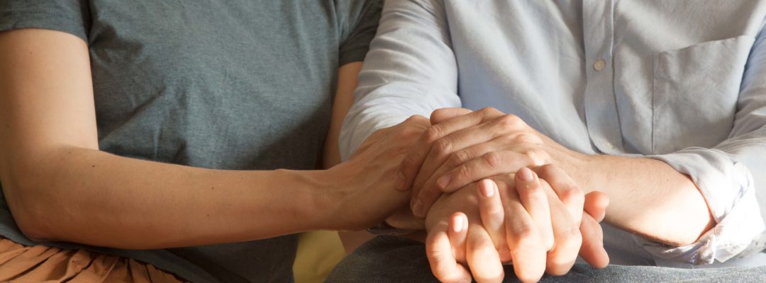 Kaksi ihmistä pitelevät toisiaan kädestä.