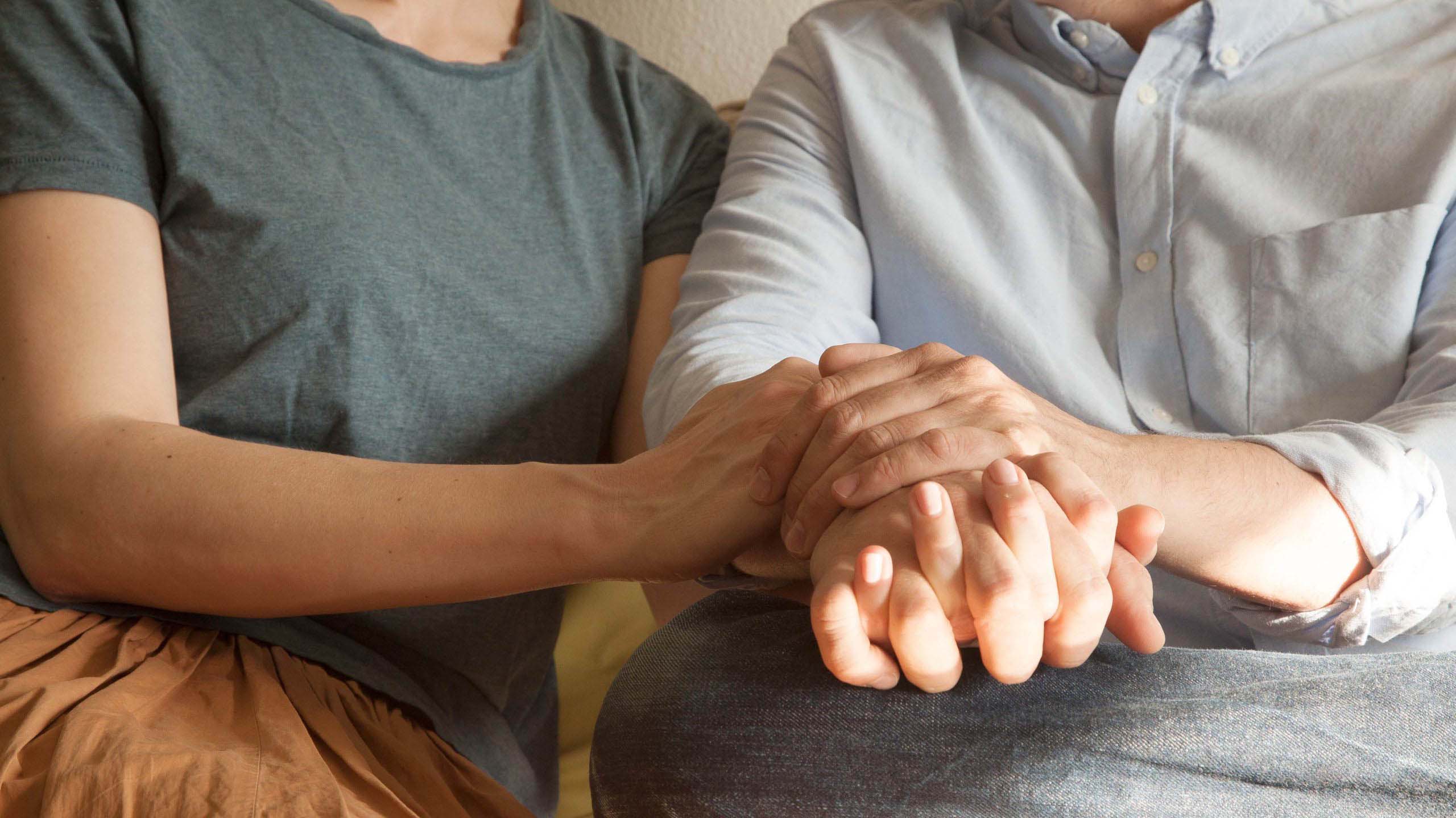 Kaksi ihmistä pitelevät toisiaan kädestä.